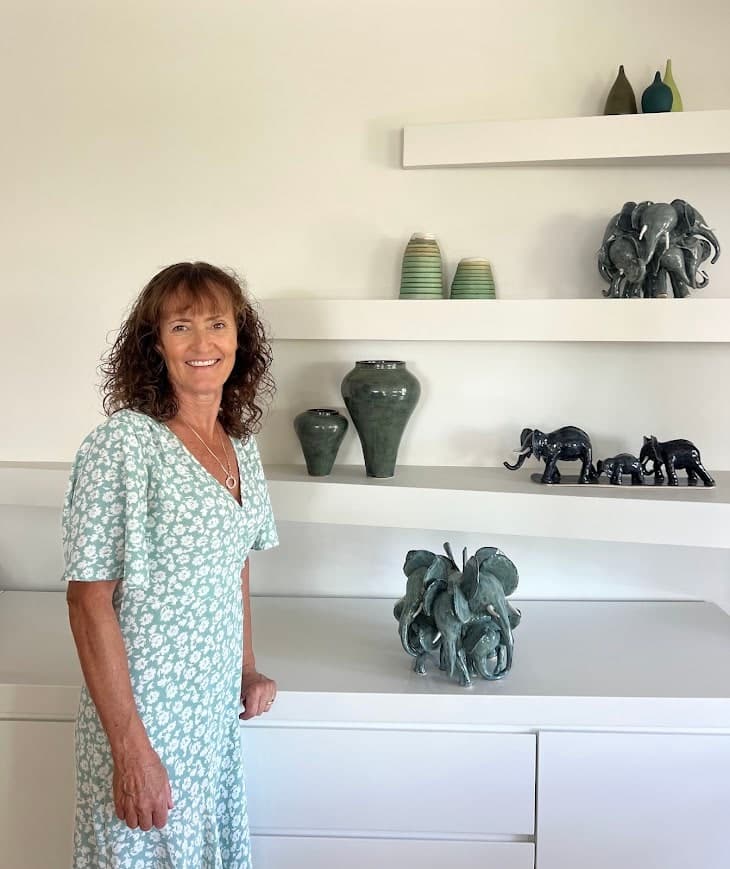 Louise Dryden in her studio, beside shelves of her ceramic vases and elephant sculptures