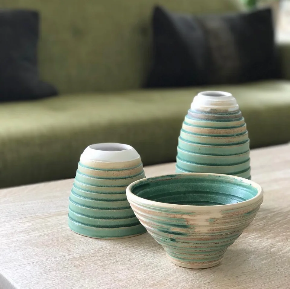 A green bowl and two distinctive ridged pots on a brown table